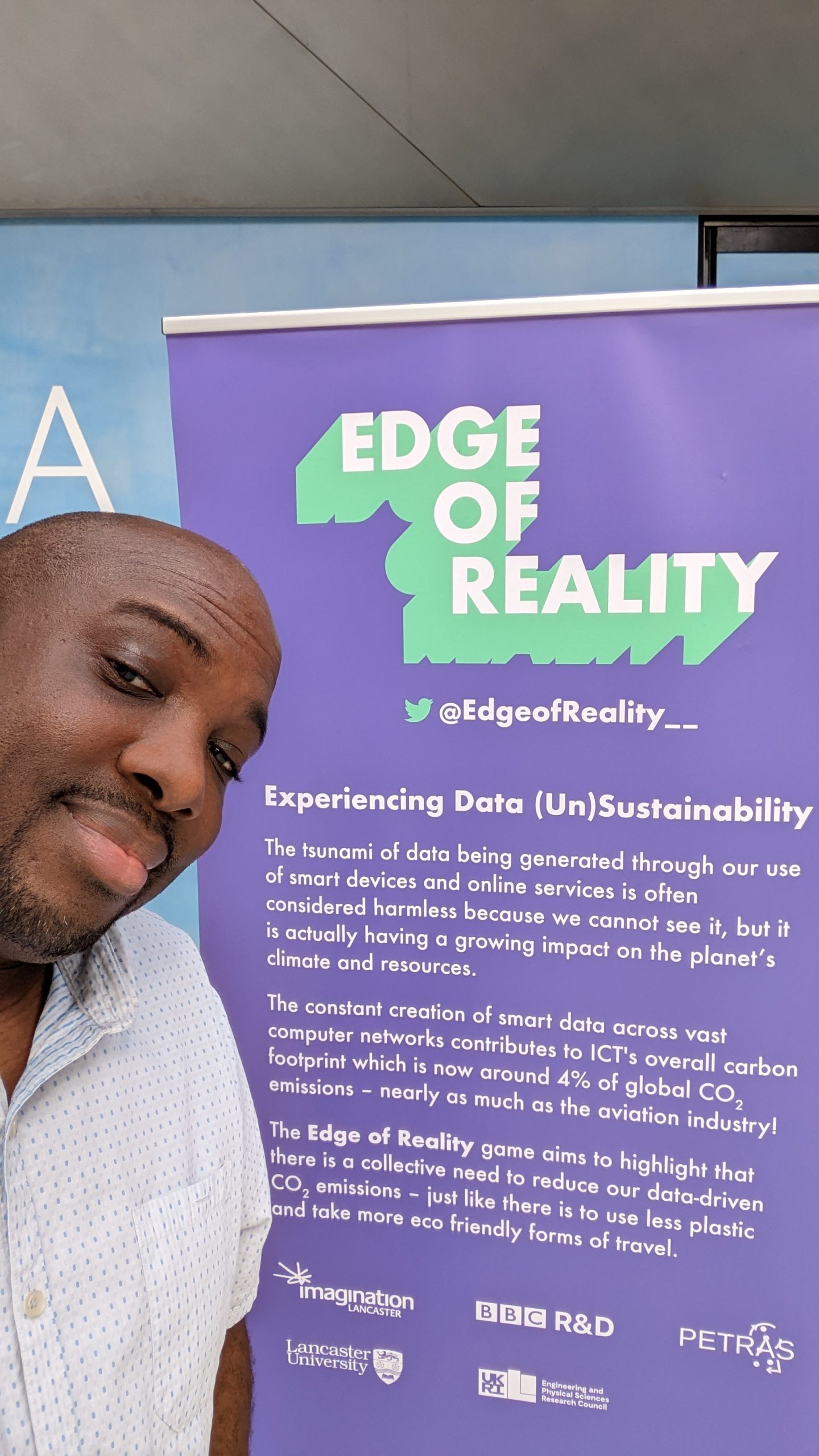 A man stood in front of a pop up banner describing the edge of reality project